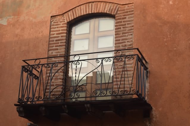 Balcón de hierro forjado en una fachada de color terracota